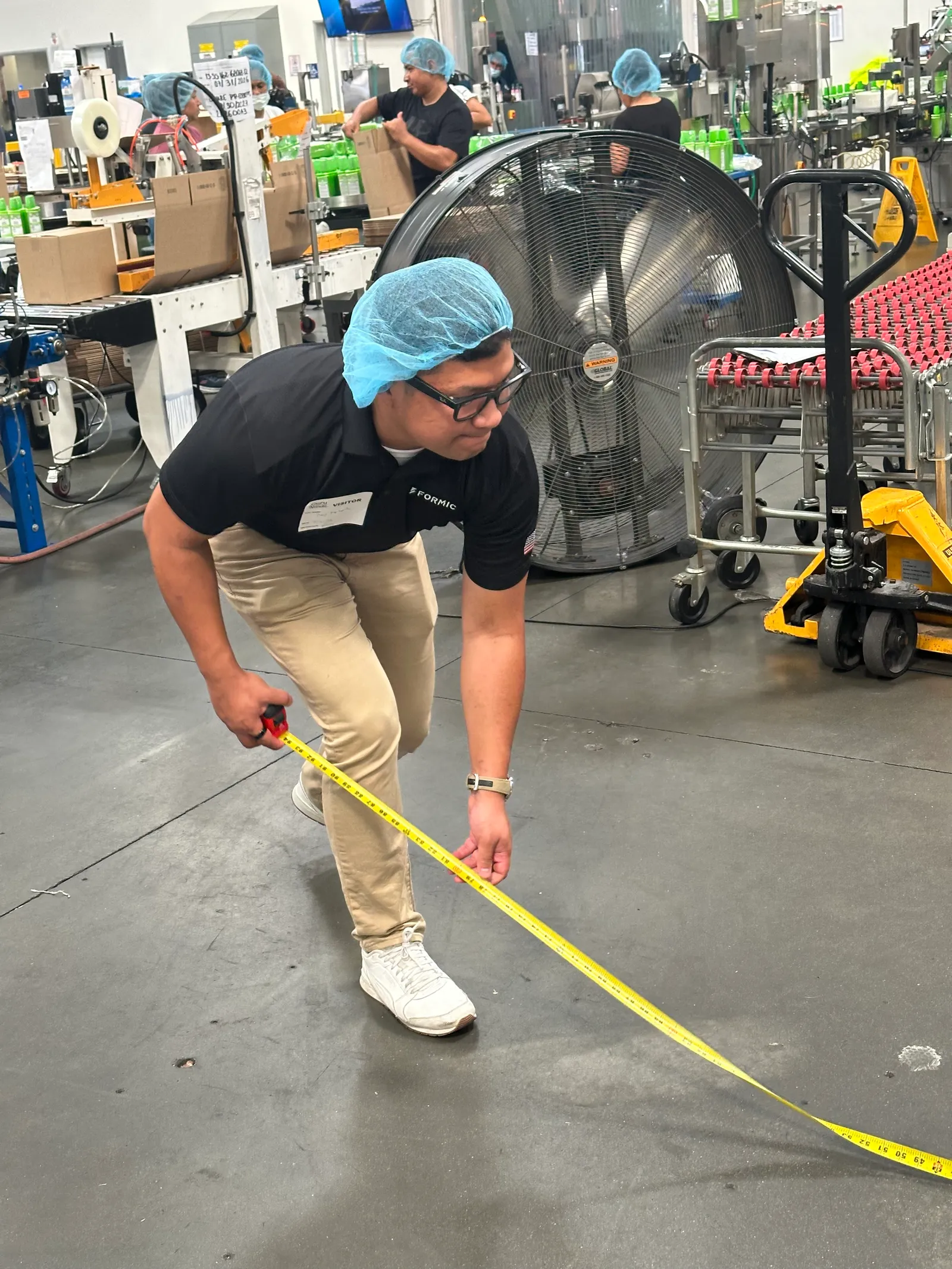 Dany Napitupulu measuring the floor space at the end of a packaging line to size a robot cell footprint