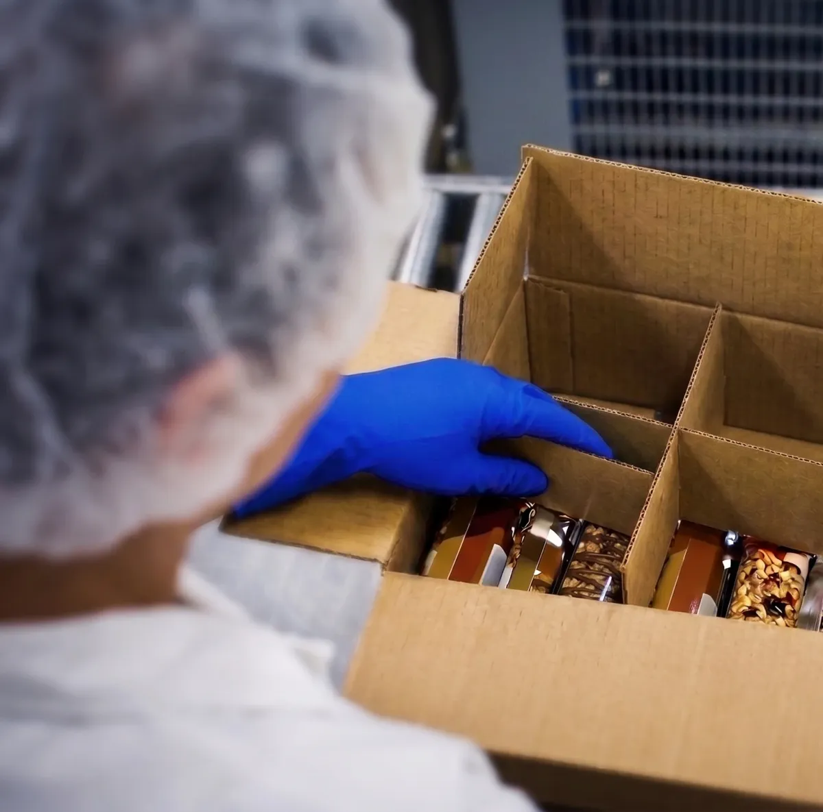 Operator hand-placing product into a partitioned case, the repetitive packing job Formic Fast Track takes over