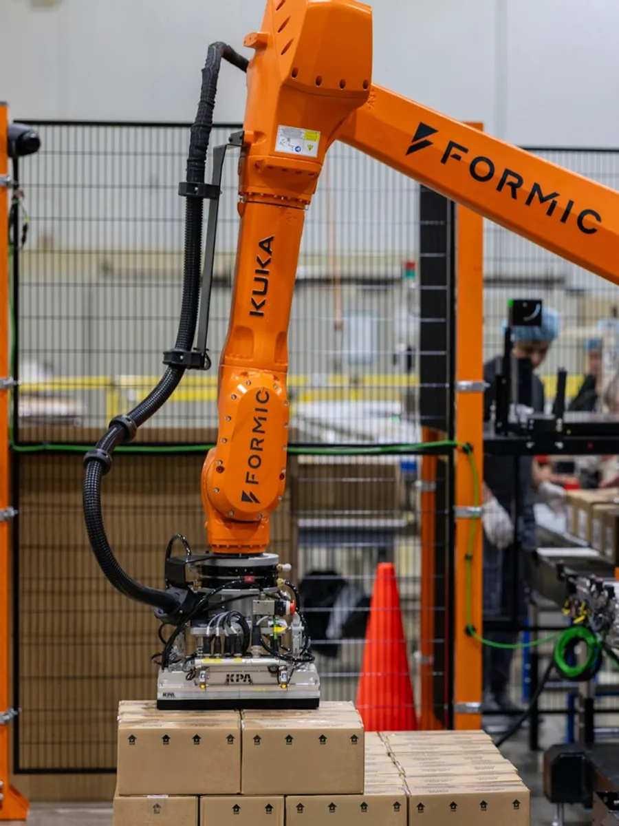 Formic industrial palletizer placing cases onto a fresh pallet at end of line