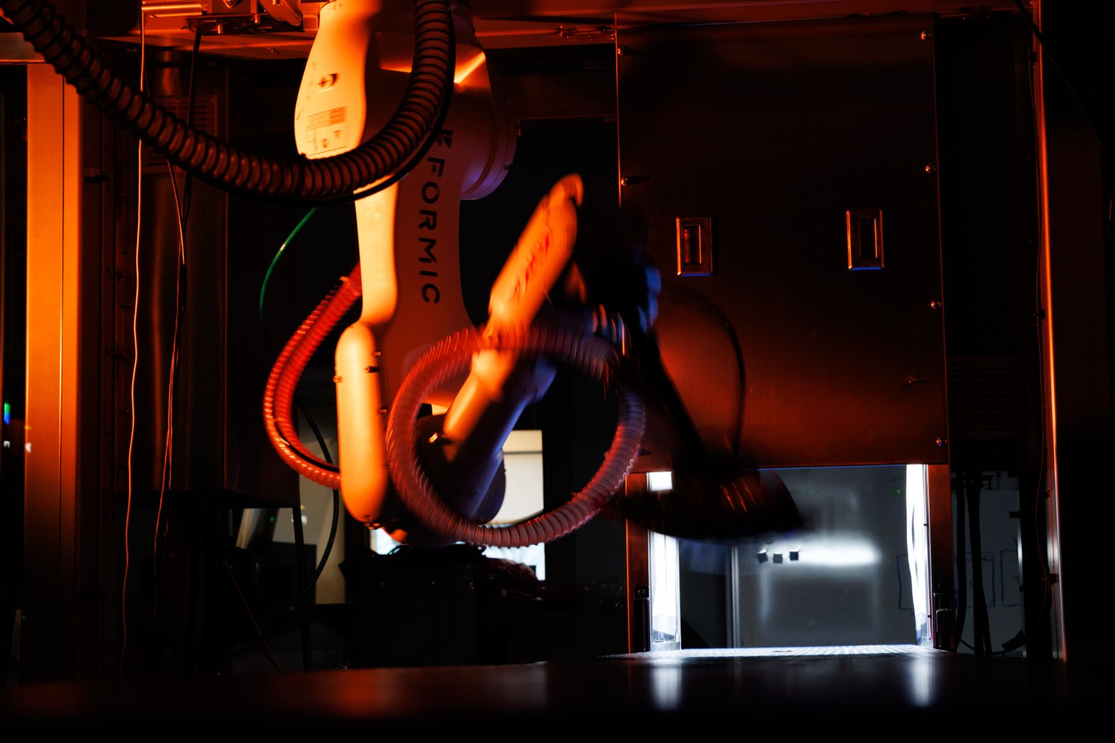 Formic robot arm at work under amber light — the next generation of capability in development