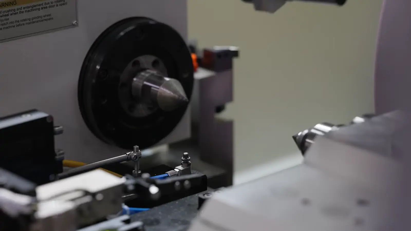 A shaft spinning in the chuck against the grinding wheel