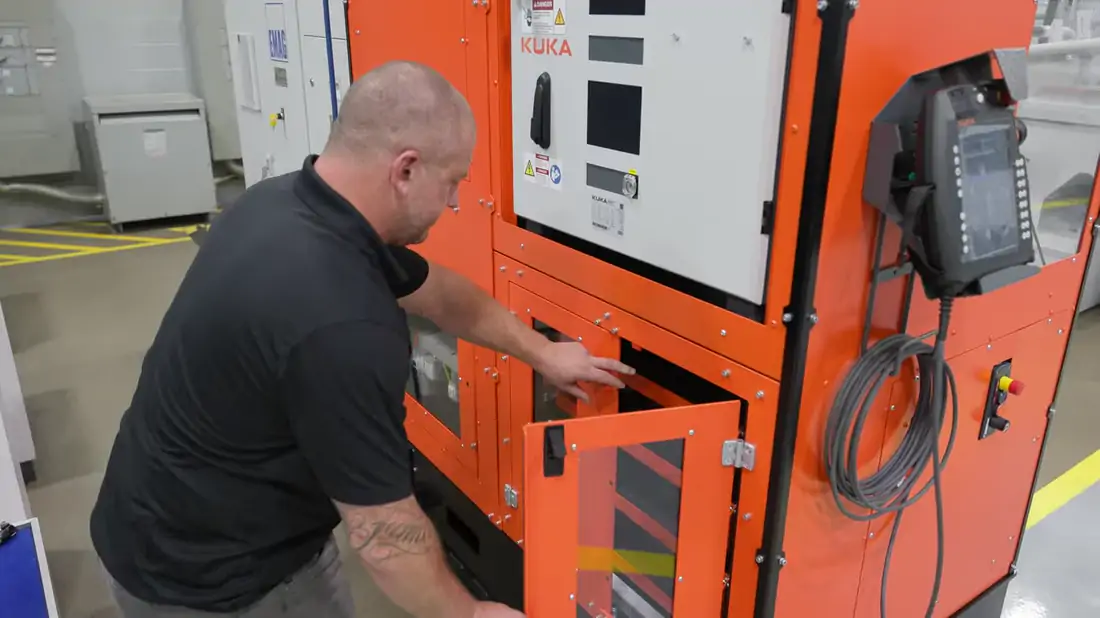 An operator opening the cell door to swap a tray, the only part of the job left to a person