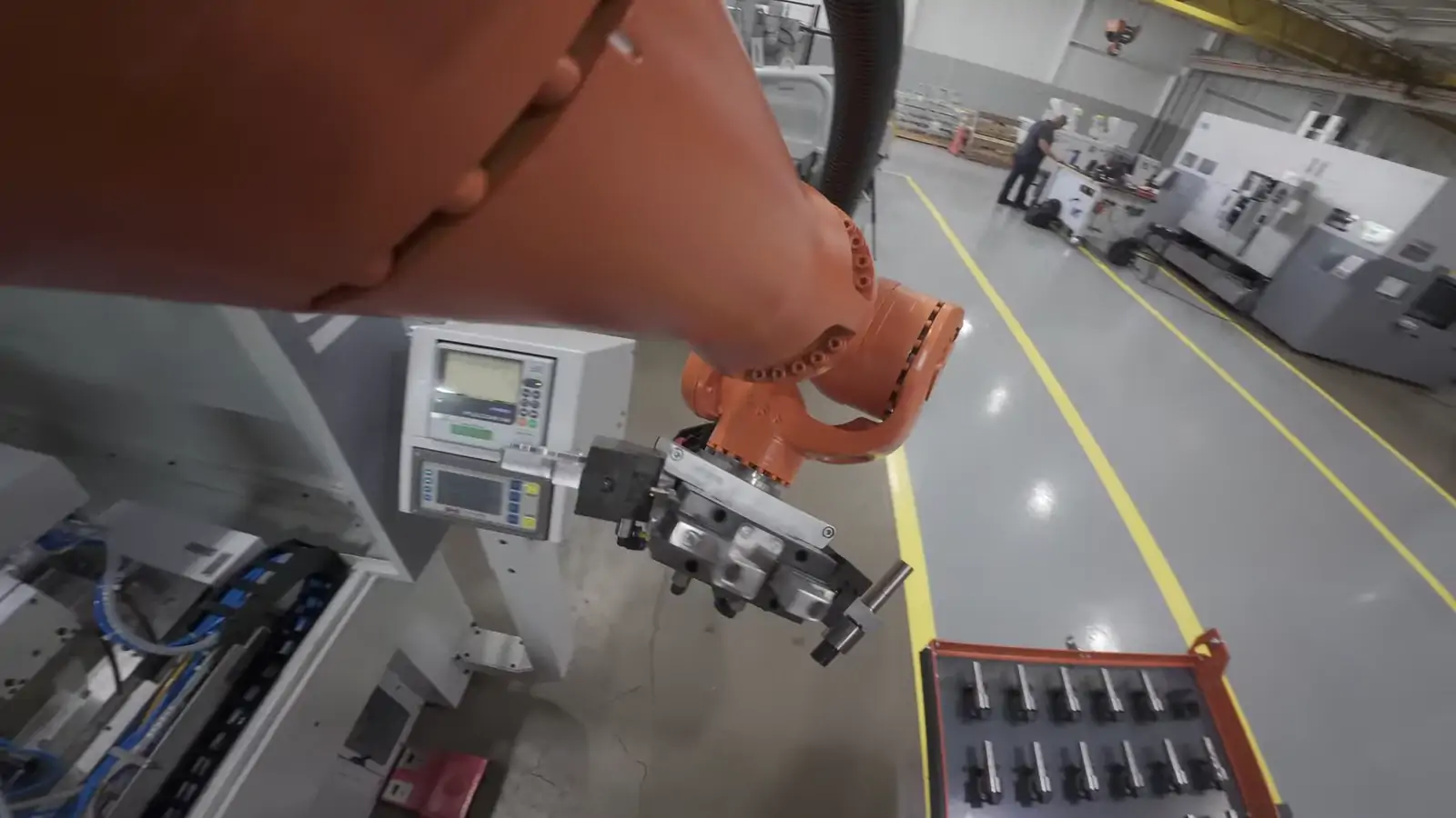 The robot carrying a staged tray of shafts to the open machine door