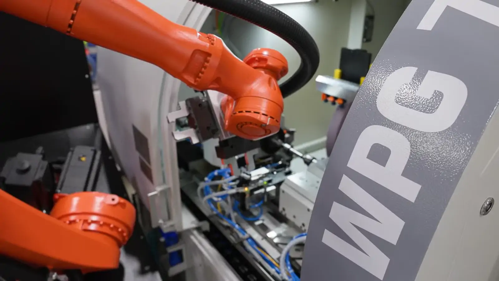 The robot working at the open machine door, tray staged alongside